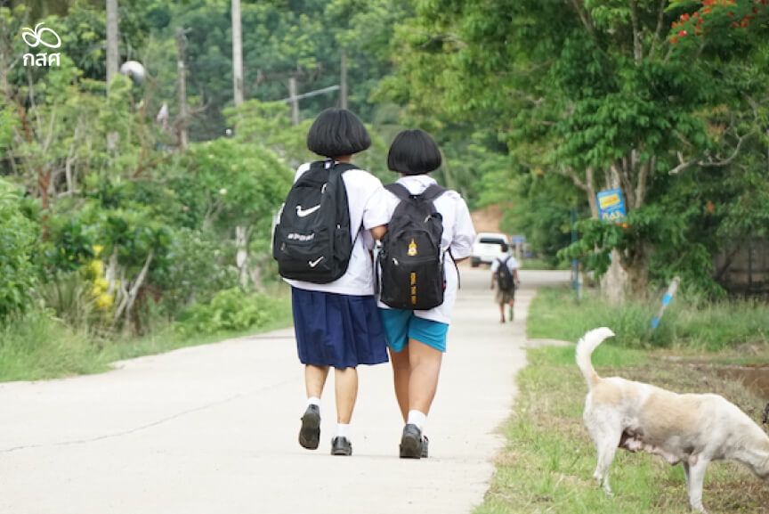 นักเรียน 2 คนเดินบนถนนในชนบท